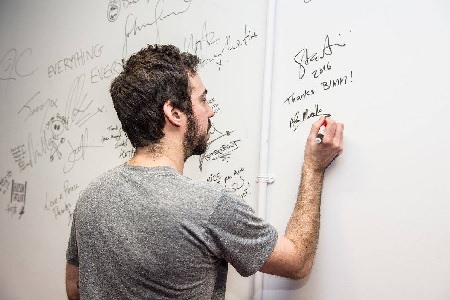 Adam Marcello writing on a whiteboard