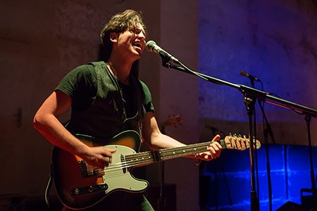 Student holding a guitar and singing