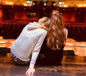 Two female students sitting together on stage