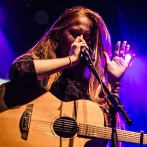 Martha Phillips singing while holding a guitar