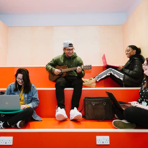 Four BIMM Birmingham students seated on orange seats