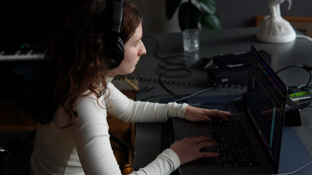 Music production student from BIMM University Berlin sits at her laptop to master a demo.