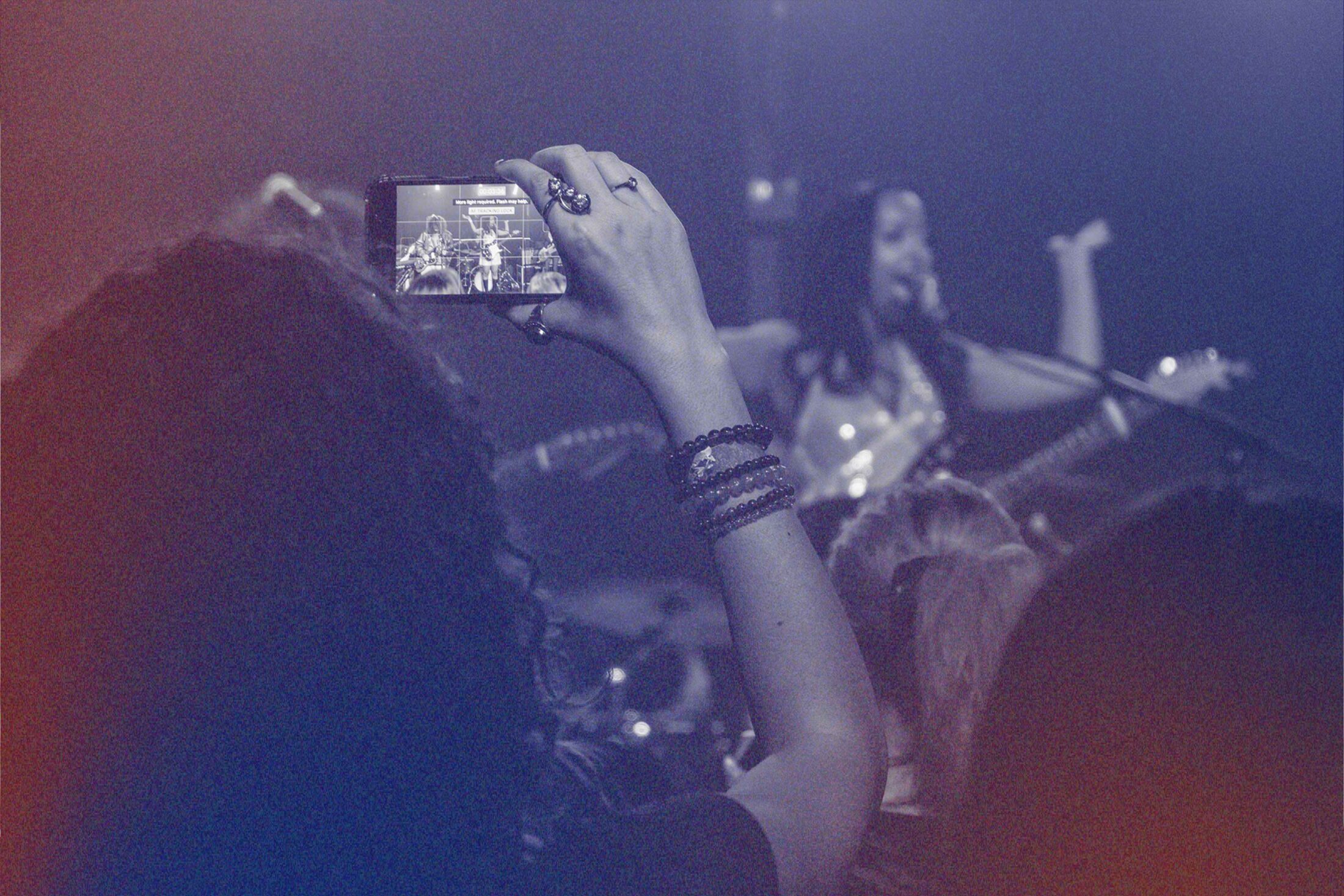 Person holding a phone recording a Live performance